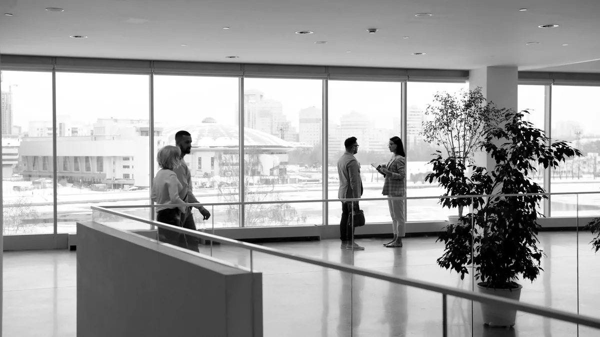 Colleagues in conversation in a glass-walled office lobby