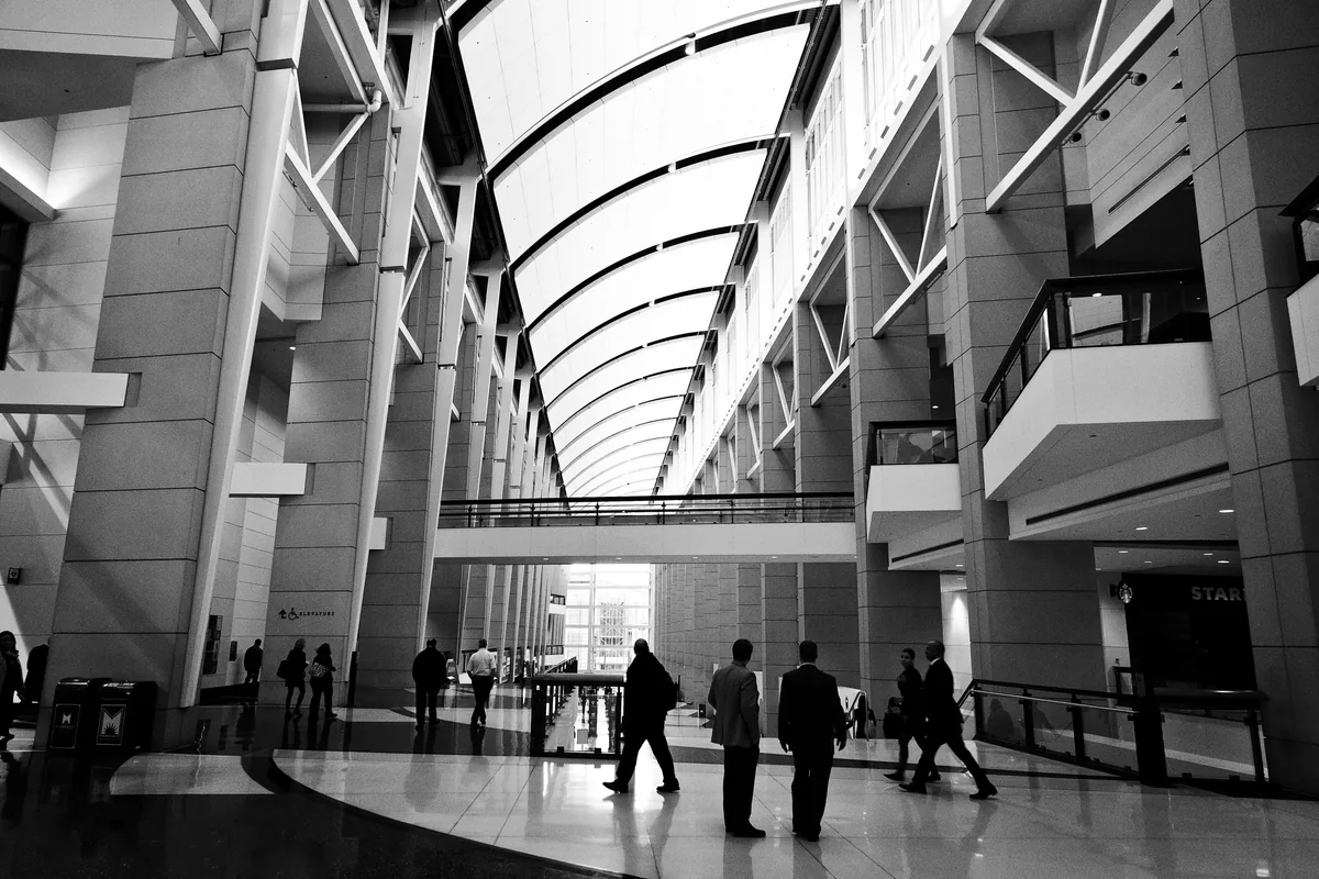 A glass atrium with people crossing the floor