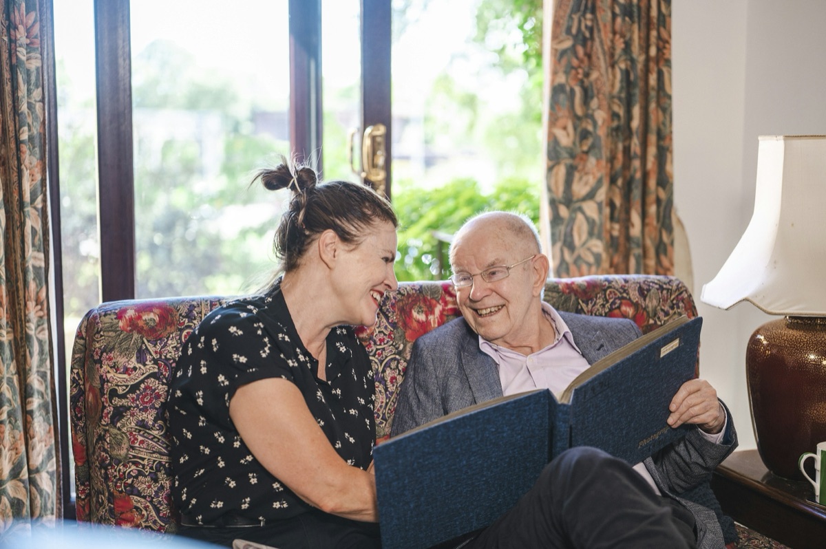 A carer and an older man looking through a photo album at home